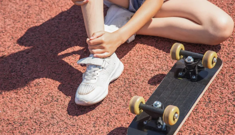 A child girl falls from a skateboard on a sports field. Skateboarding. A child rides a skateboard