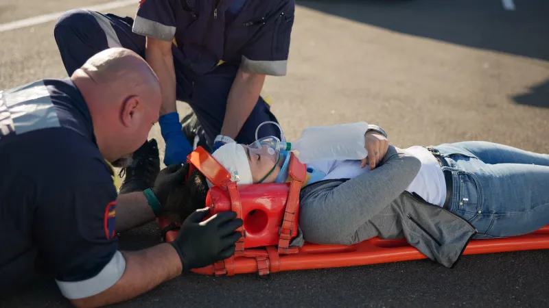 Two rescuers were helping a woman lie down on a stretcher and giving her first aid.