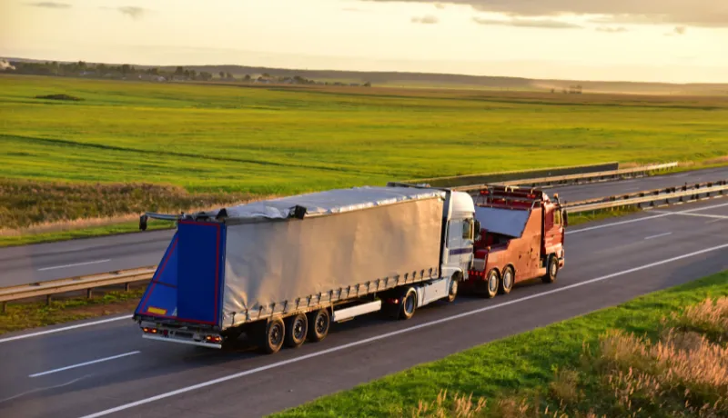Heavy Recovery Truck Tows a Semitrailer truck on highway.