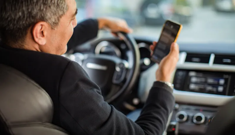 Middle aged man using a smart phone while driving a car
