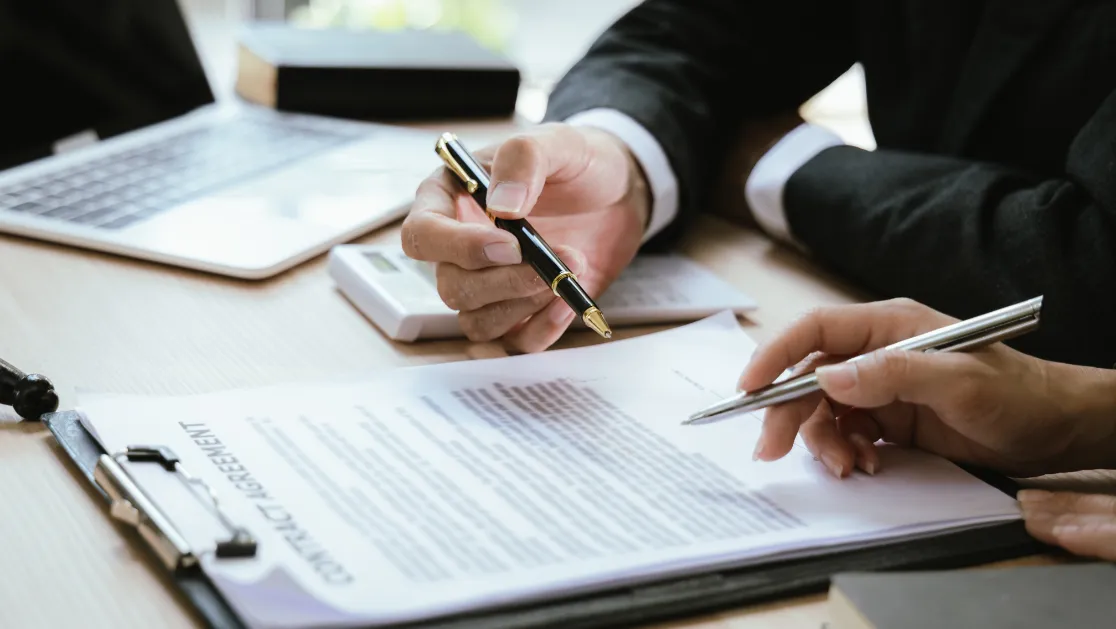 Close up of male lawyer working with contract documents and wooden hammer on table in courtroom.