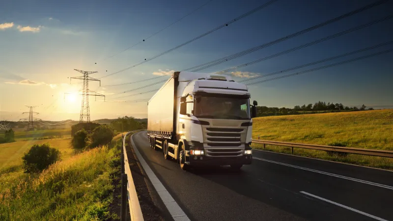 Large Transportation Truck on a highway road through the countryside at sunset