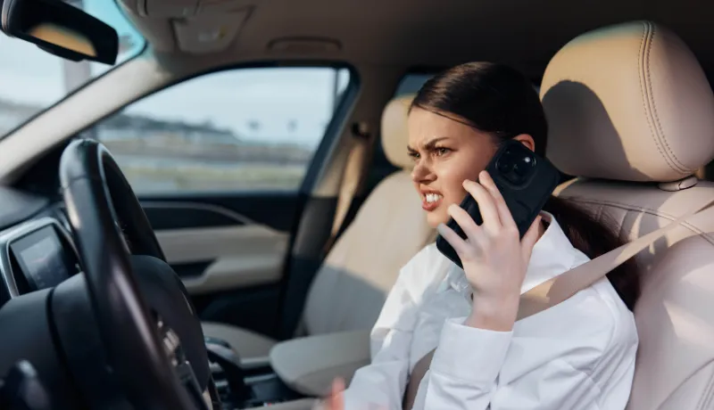 holding the steering wheel while talking on a cell phone, illustrating a distracted driving scenario