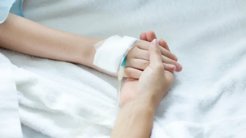 Woman holding children hand in hospital.