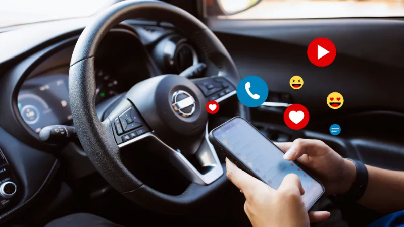 Close-up of a person holding a smartphone while driving, emphasizing the dangers of distracted driving and road safety concerns