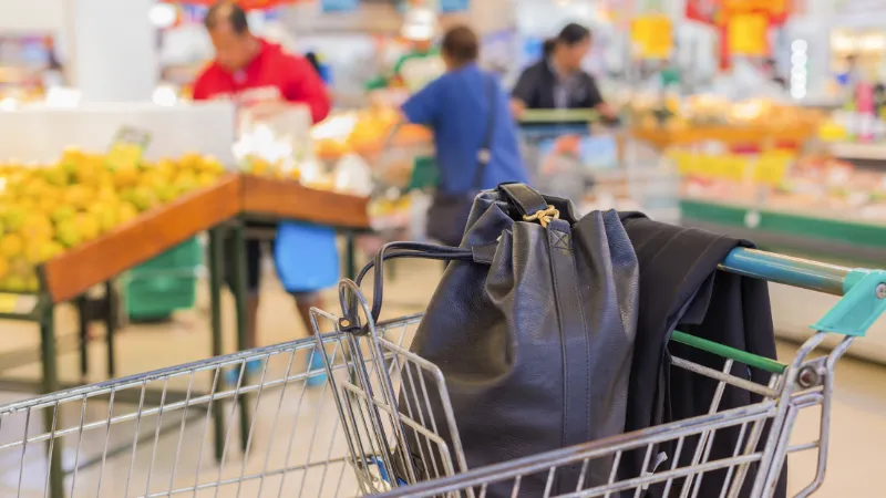 Woman's bag in the trolley at the supermarket and supermarket blur background