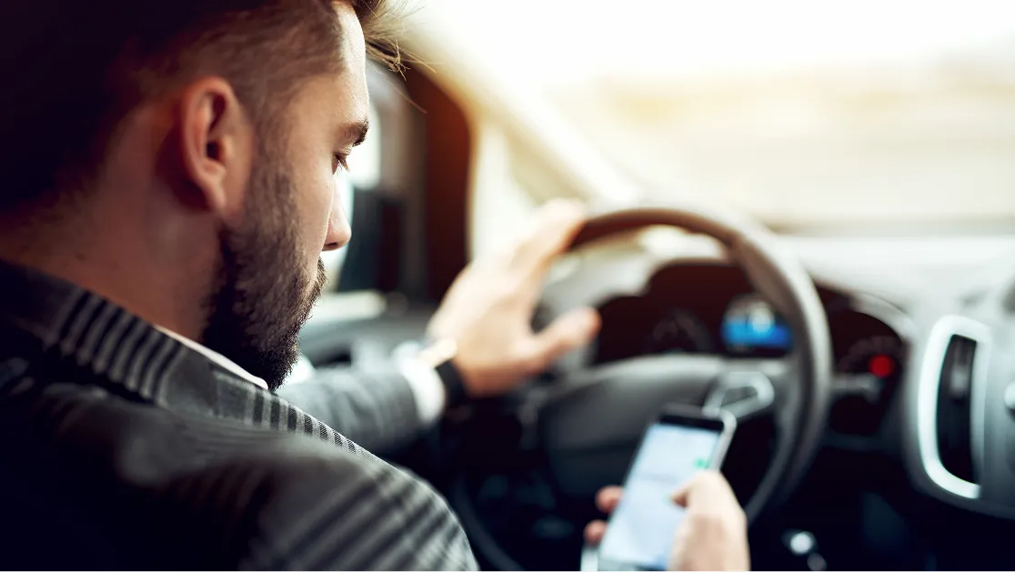 A man driving a car while using his cellphone.