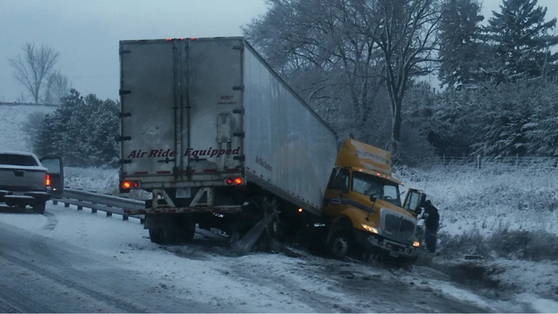 A truck accident on an icy road caused by snow and heavy fog.